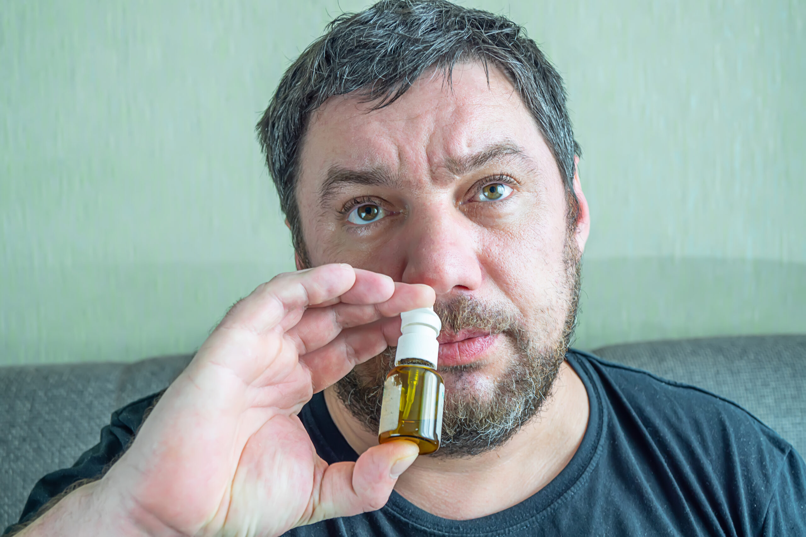 man with runny nose treats nose with nasal spra